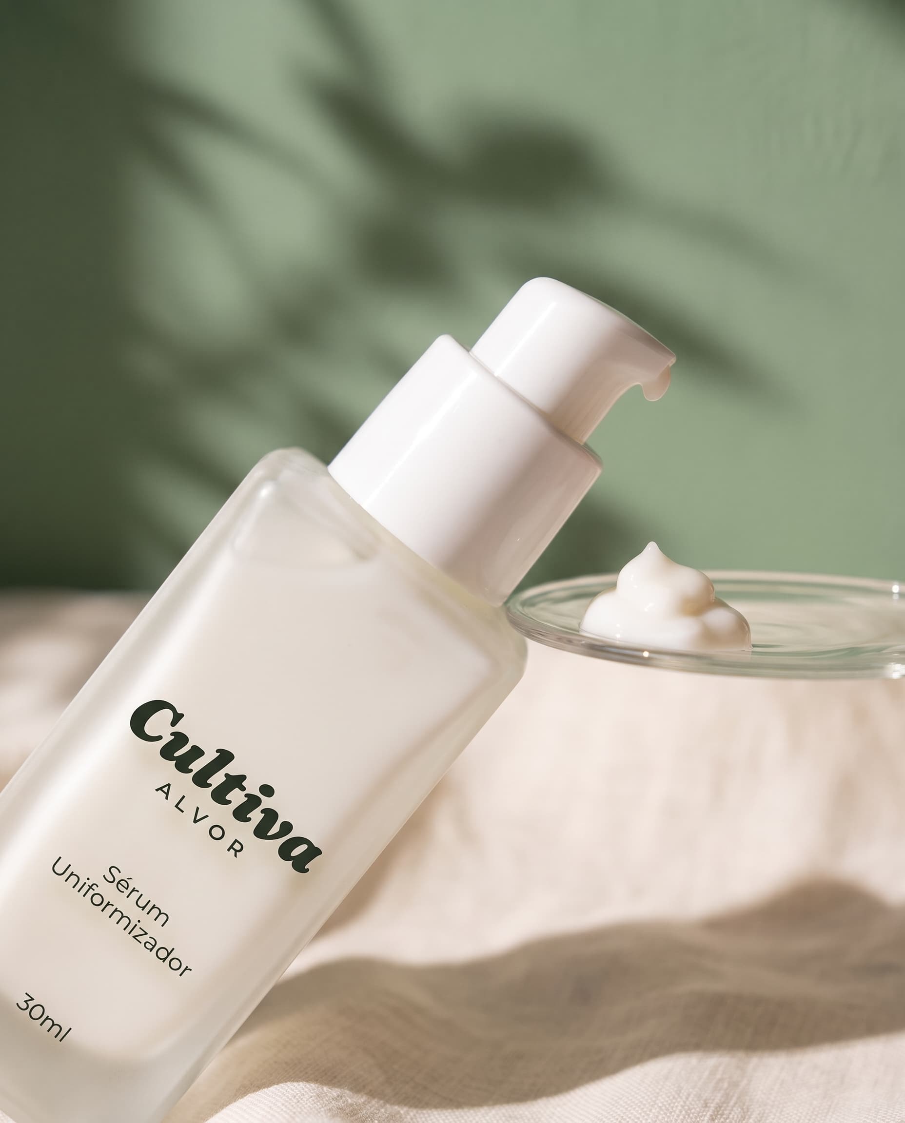 Detalhe do pump dispensando uma gota de creme branco do Sérum Uniformizador Cultiva